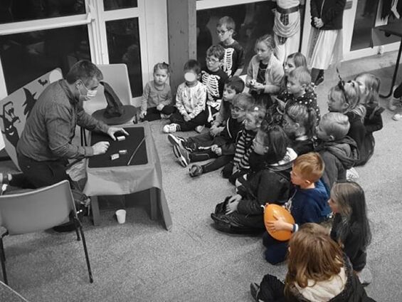 Enfants assis par terre regardant un spectacle de magie