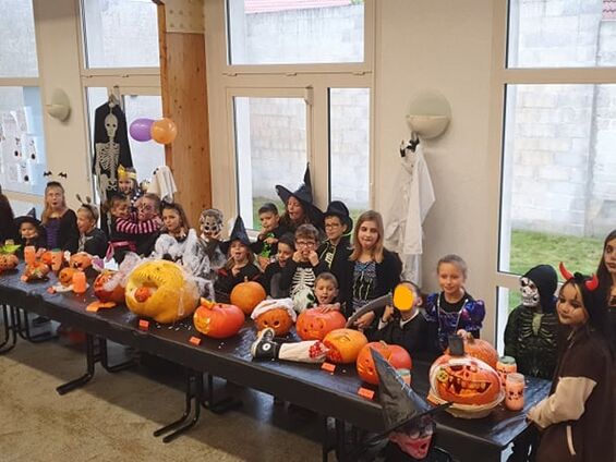 Enfants rassemblés derrière leur sculpture de citrouille d'Halloween